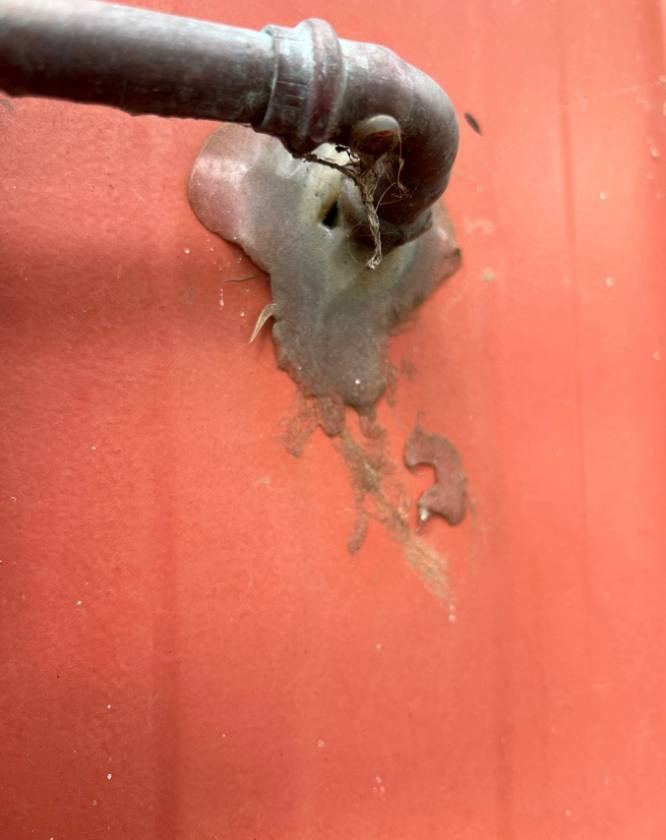 Pipe penetrating red wall cladding with smeared sealant