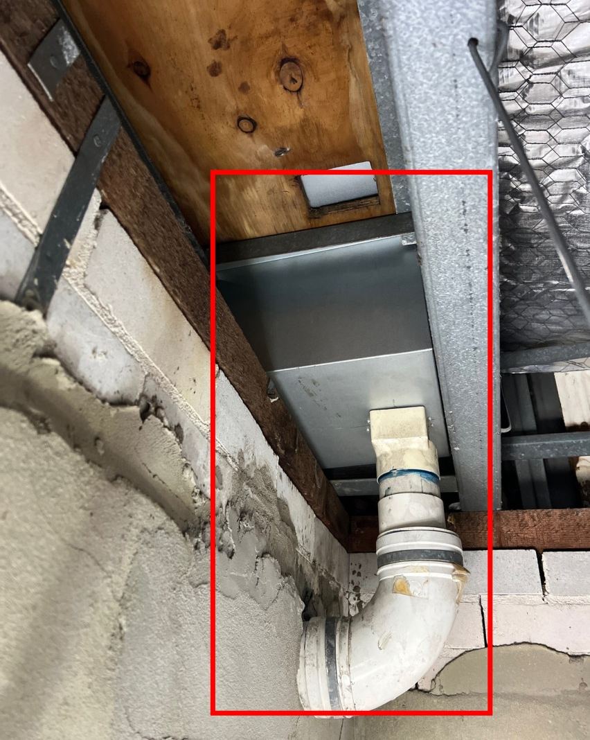 Downpipe below a box gutter sump in a ceiling space, marked in red