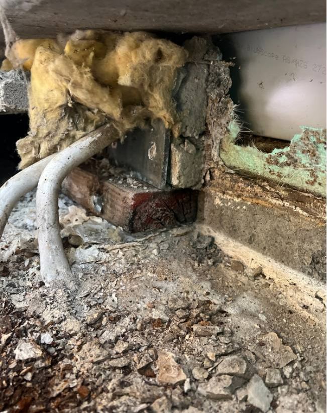 Exposed wall base showing failed waterproof membrane and wet insulation