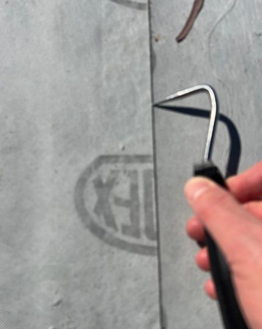 Hand holding a probe tool along a welded membrane seam