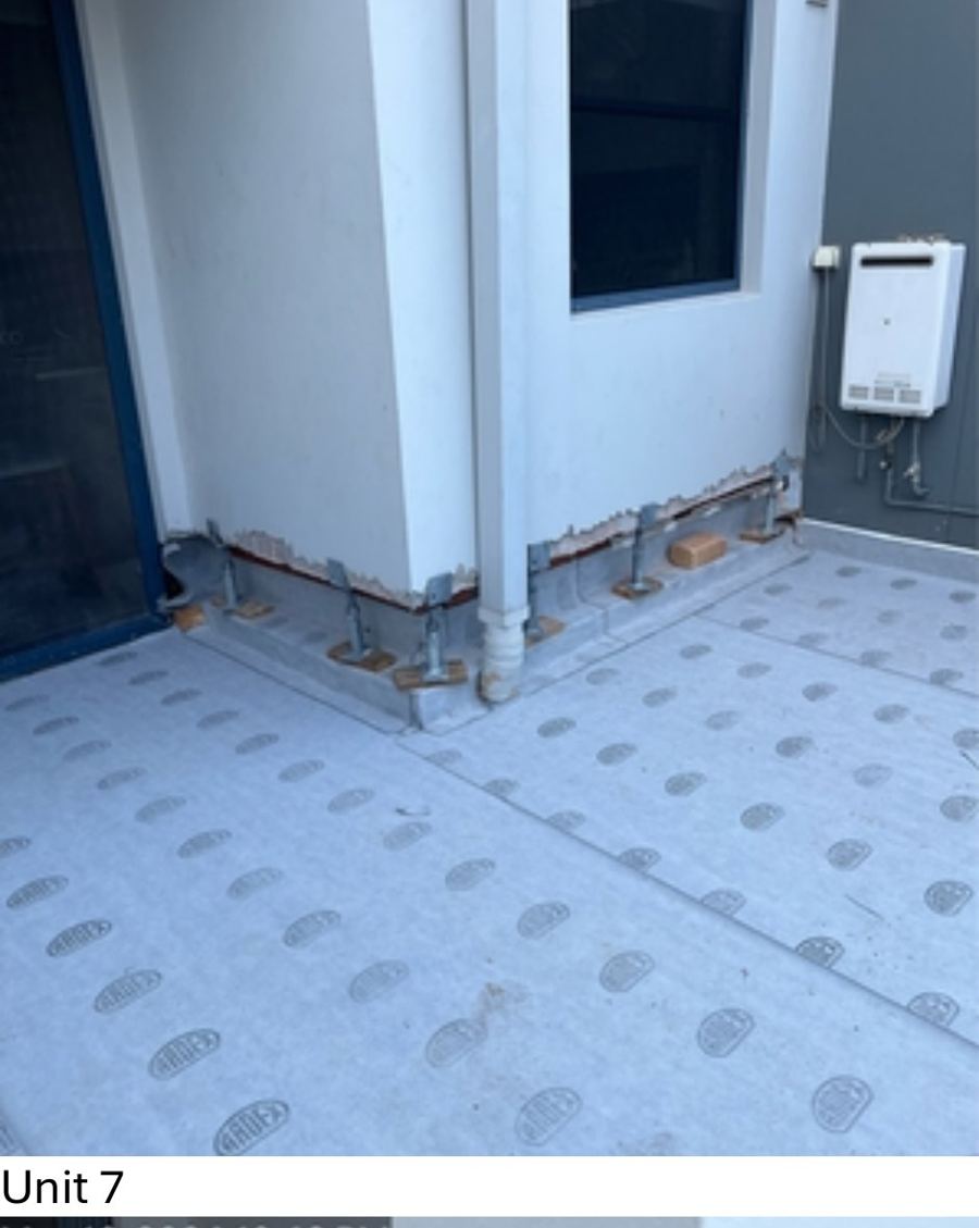 Balcony with new grey sheet membrane and the bottom brick courses removed along the wall for cavity flashing