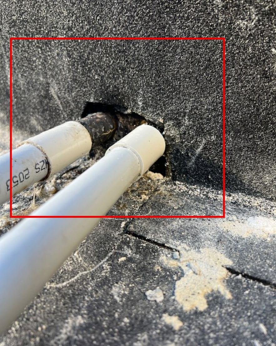 Two conduits passing through a membrane-lined wall with an open gap around them, marked in red