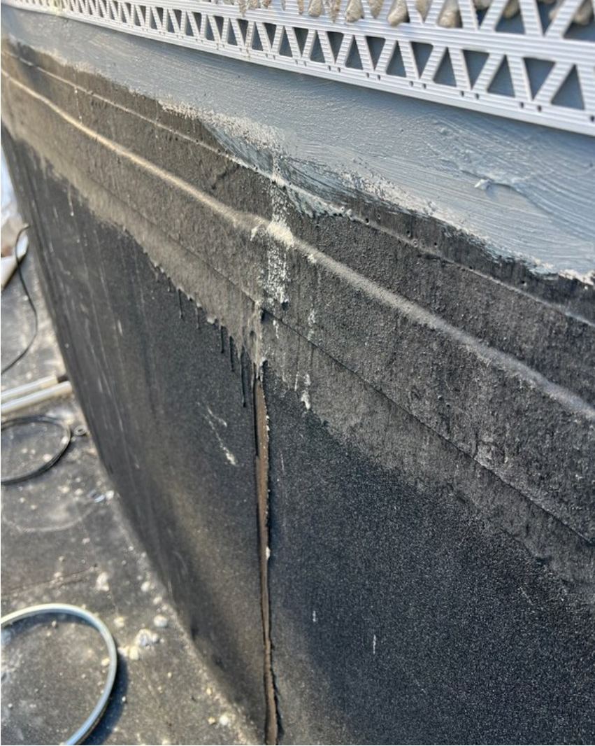 Top edge of a sheet membrane turned up a wall and finished under render