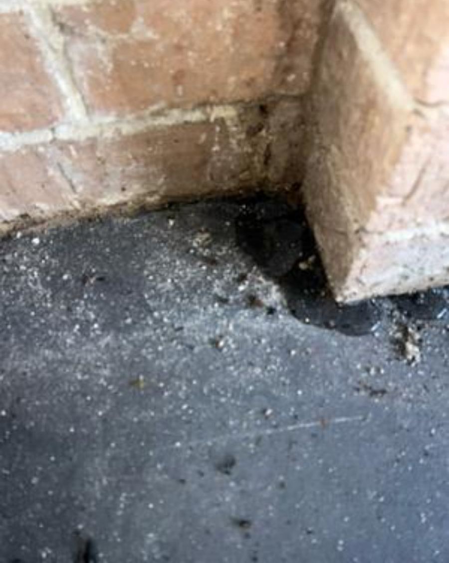 Wet patch on garage floor at base of brick wall