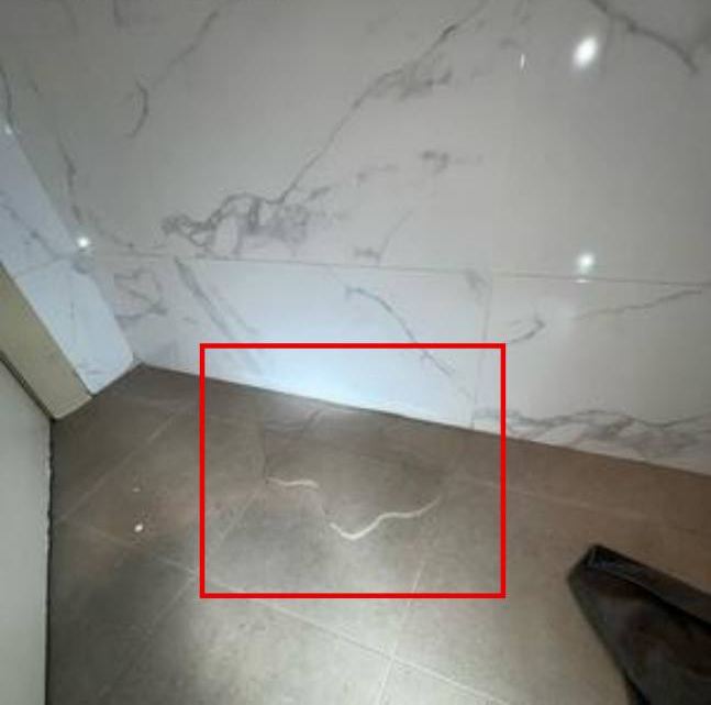 Bathroom floor with water emerging at base of wall, marked in red